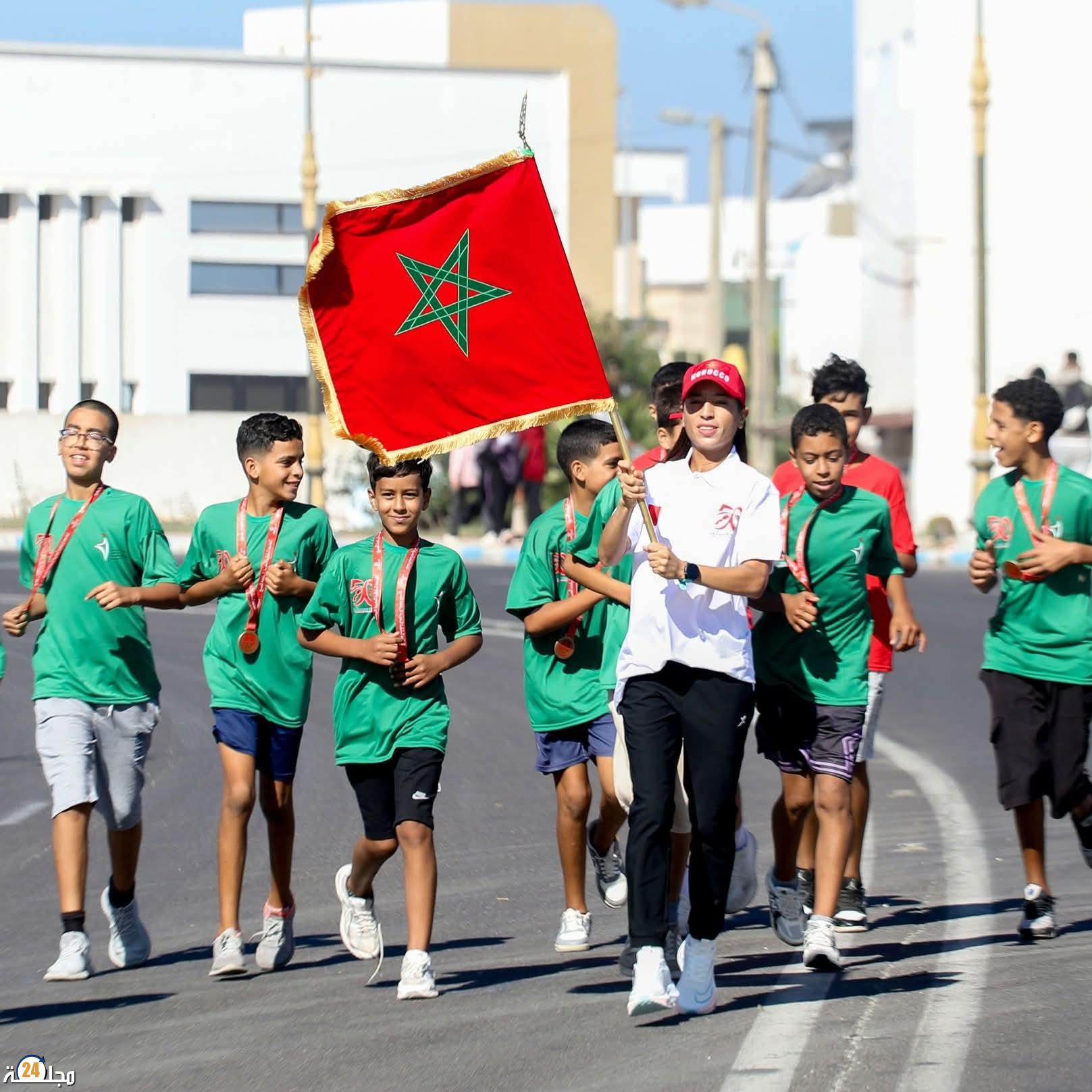 فاطمة الزهراء كردادي حاملة العلم الوطني في المرحلة السادسة من” سباق التناوب الرمزي المسيرة الخضراء” بين آسفي والصويرة